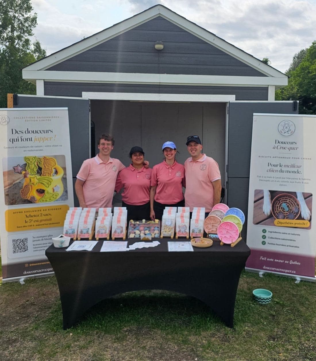 The Douceurs à Croc-quer team at their market booth, behind a table covered with treat bags and cookie cutters